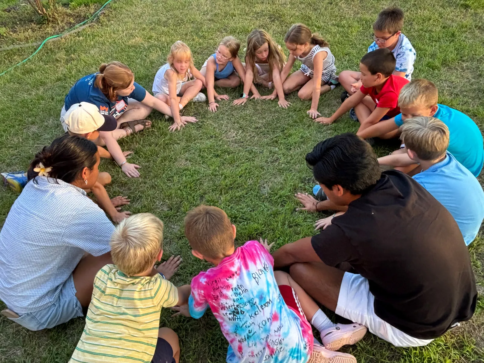 Children sitting in a circle on the church lawn with their leaders